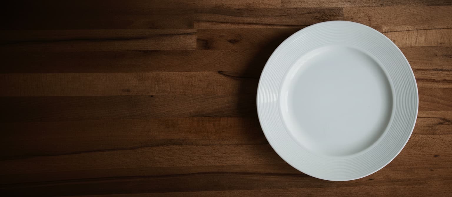 Empty white plate on wooden table